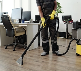 Büroreinigung - Mann im braunem Overall und gelben Handschuhen sagt den Boden in einem Büro - Clean Team Solingen